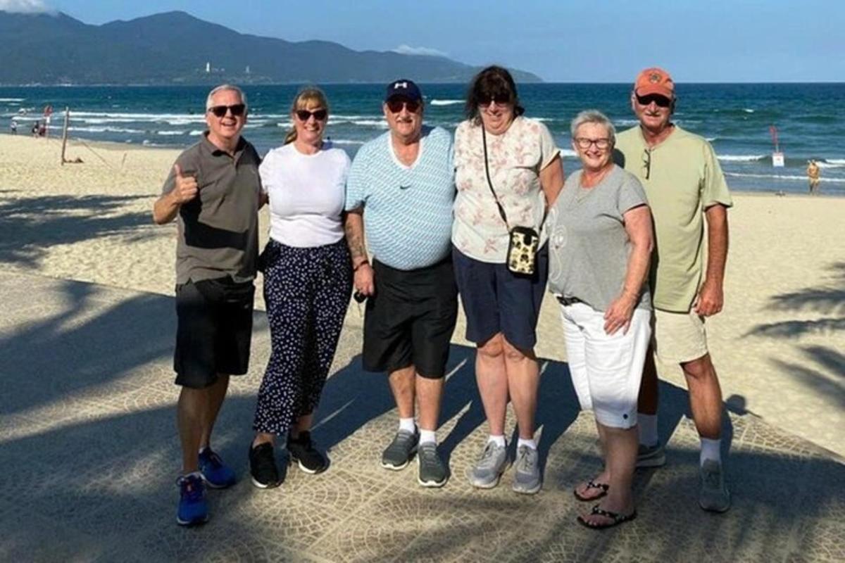 een groep mensen die poseren voor een foto op het strand