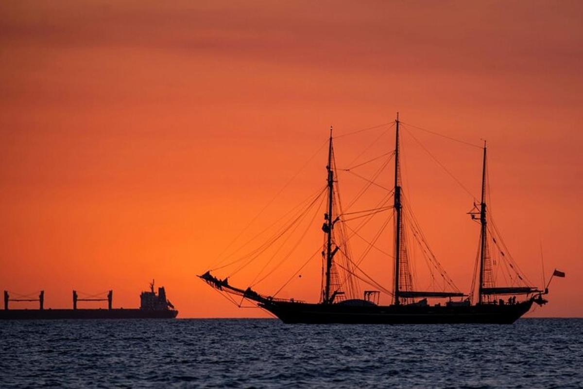 a sail boat in the ocean at sunset