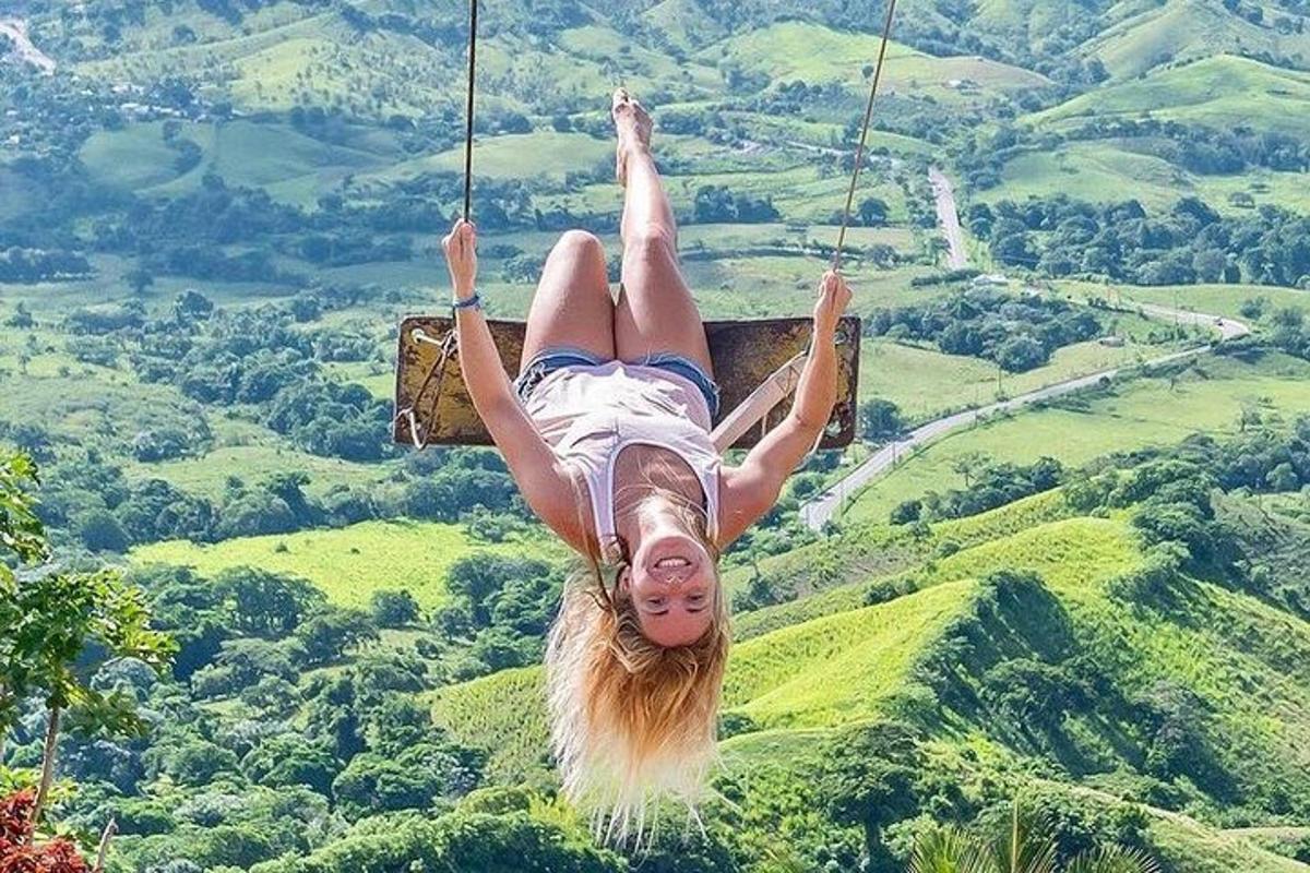 a woman swinging on a zip line in the mountains