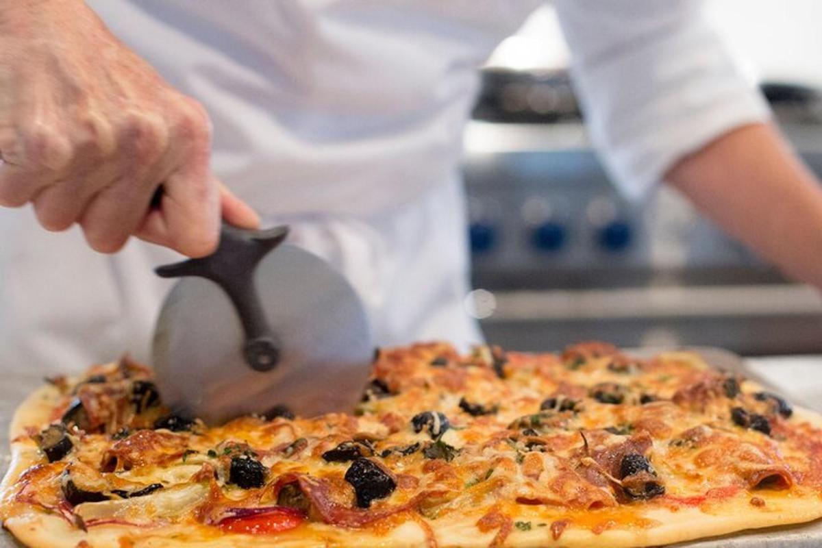 oseba, ki reže pico z rezalnikom za pico