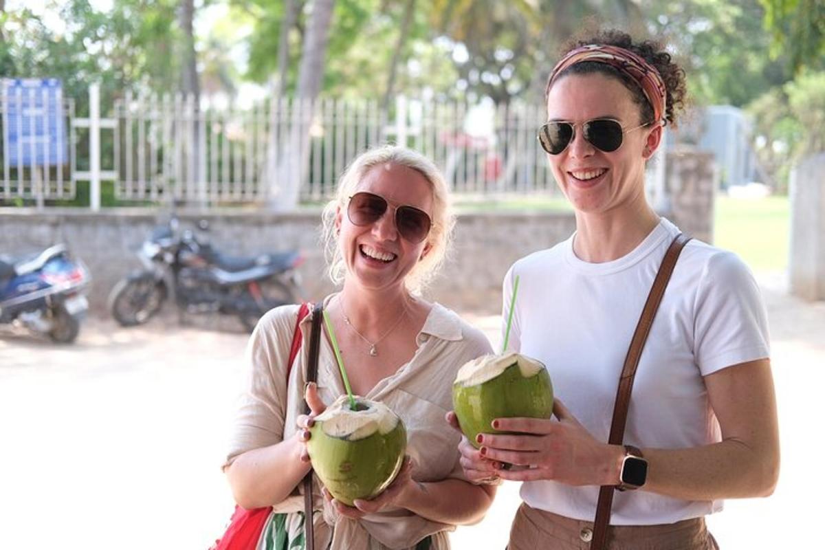 two women standing next to each other holding coconuts