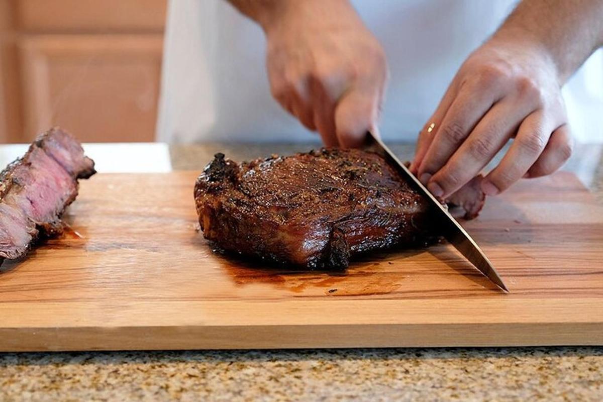 una persona tallant un bistec en una taula de tallar amb un ganivet