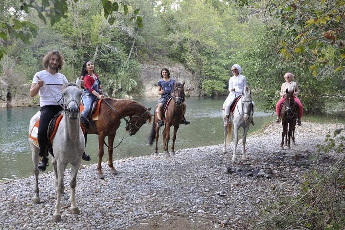 um grupo de pessoas andando a cavalo ao longo de um rio