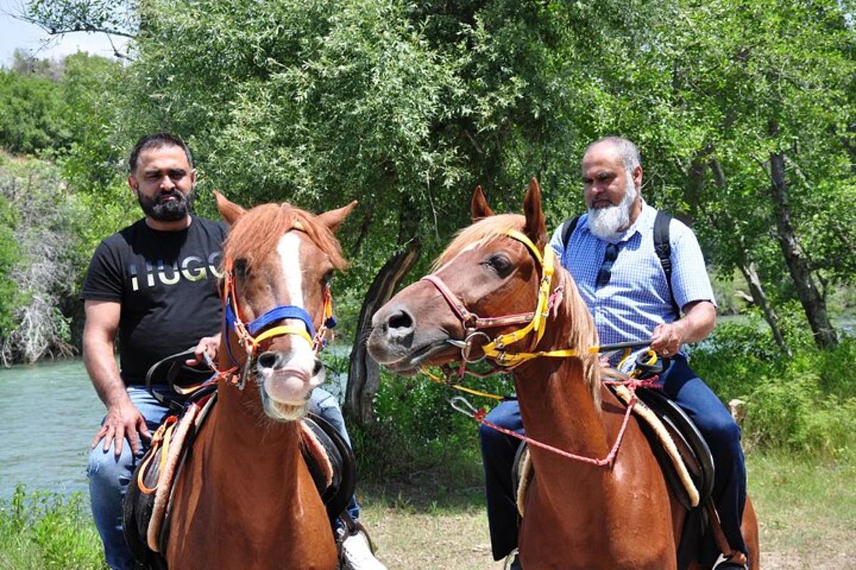 dois homens cavalgando perto de um rio