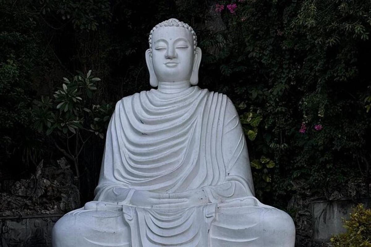 Una gran estatua blanca sentada en un jardín.