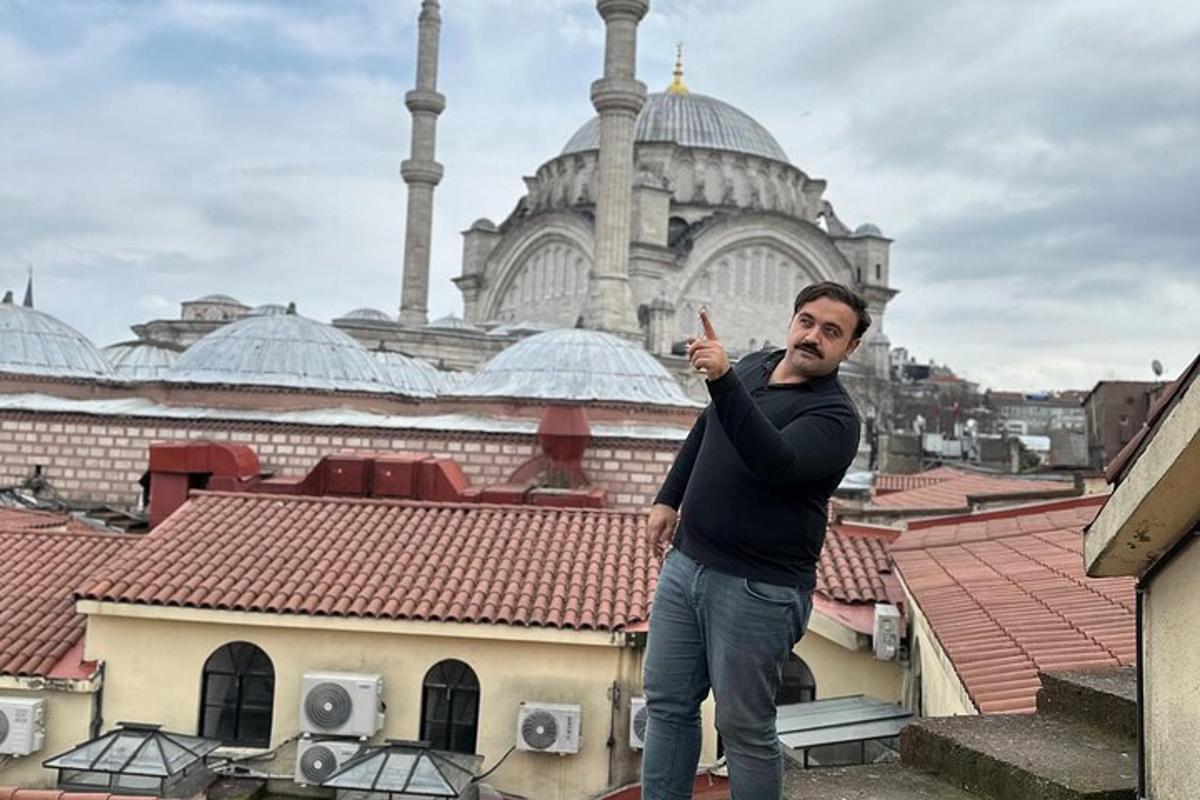 Ein Mann steht auf dem Sims eines Gebäudes mit einer Moschee