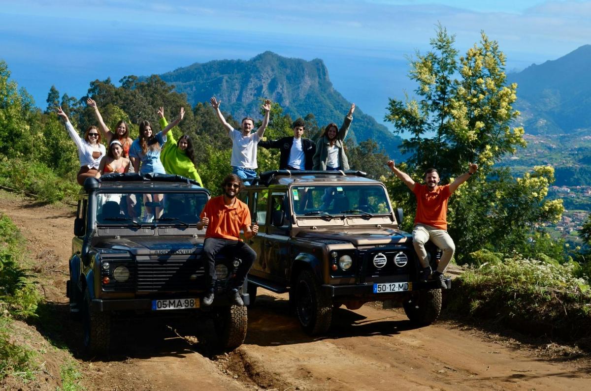 a group of people sitting on top of their jeep on a dirt road