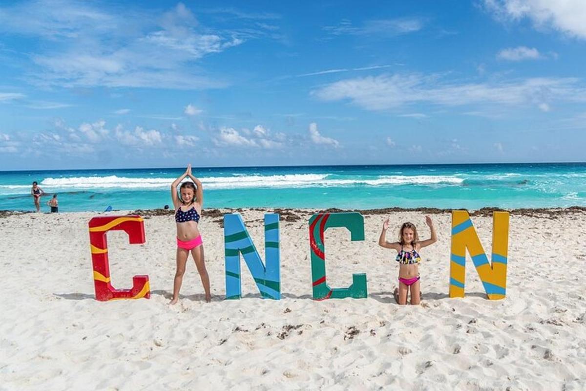 two girls standing in front of a sign on the beach