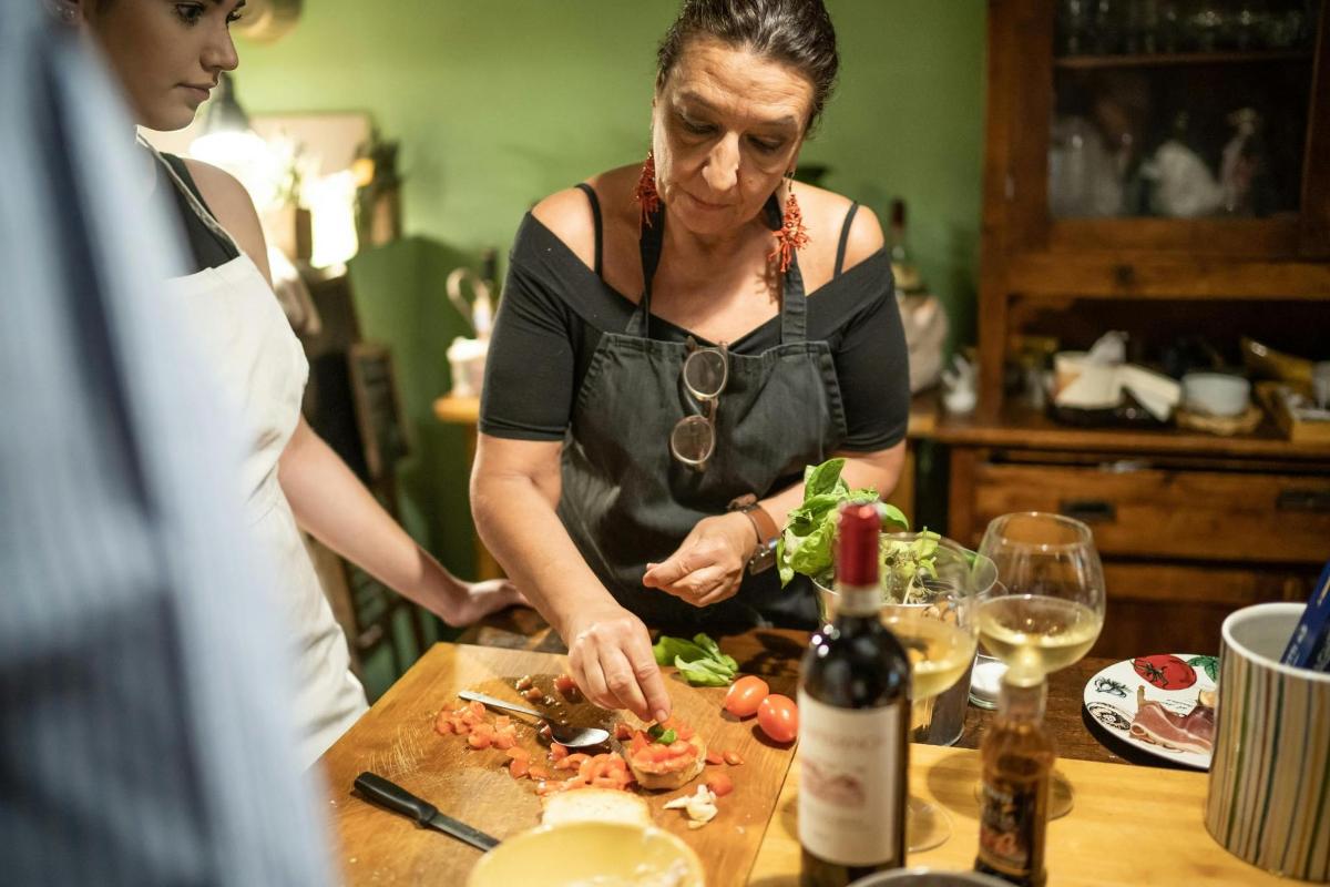 zwei Frauen bereiten Essen auf einem Schneidebrett mit einer Flasche Wein zu