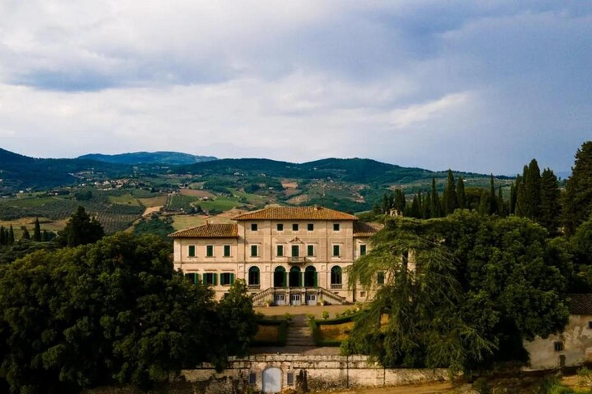 a large building with trees and mountains in the background
