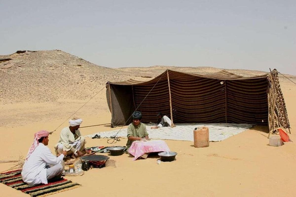 quattro persone sedute davanti a una tenda nel deserto