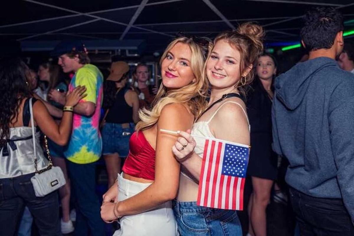 duas mulheres em pé no meio da multidão em uma festa