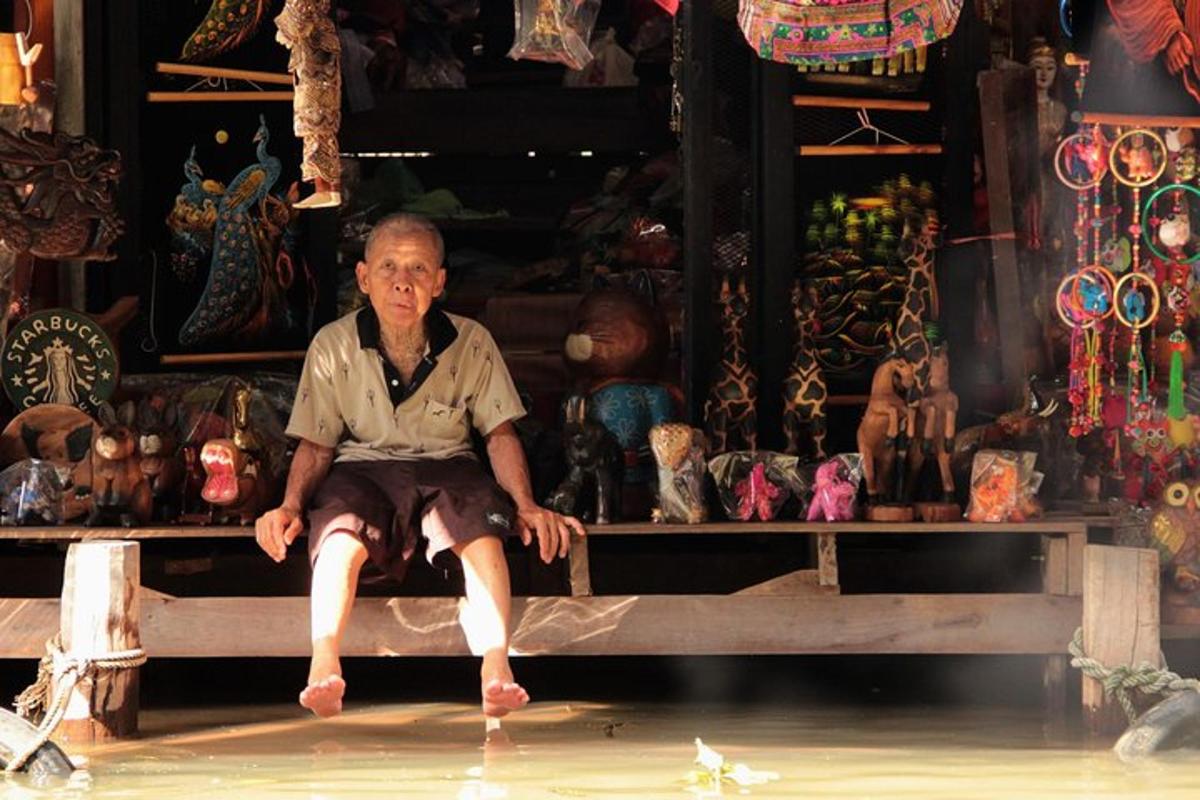 ชายชราคนหนึ่งนั่งอยู่บนม้านั่งในร้านค้า