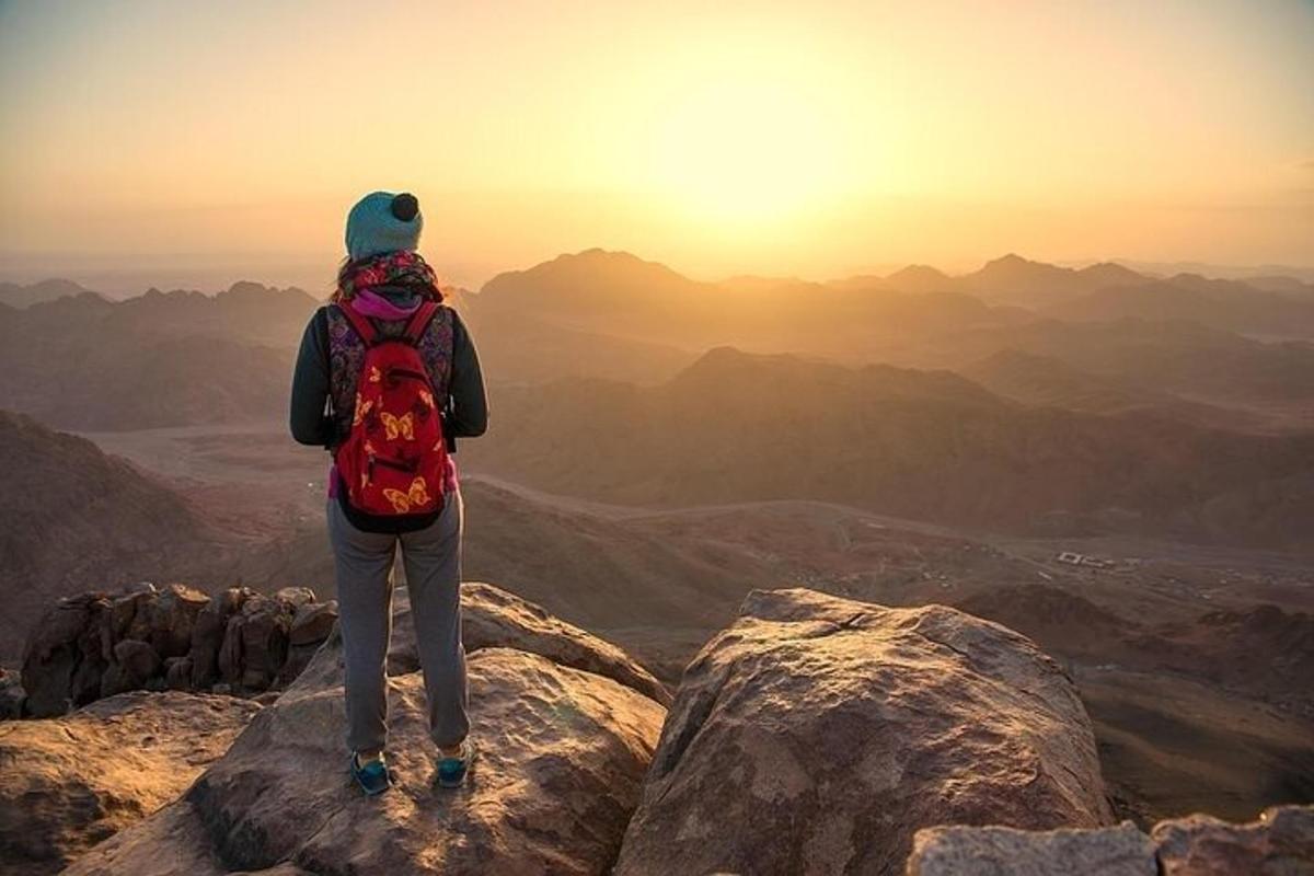seseorang dengan beg galas berdiri di atas gunung
