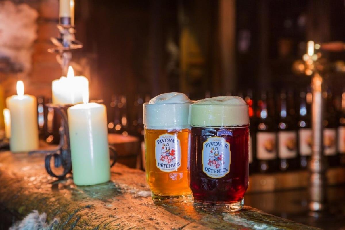 two glasses of beer sitting on a table with candles