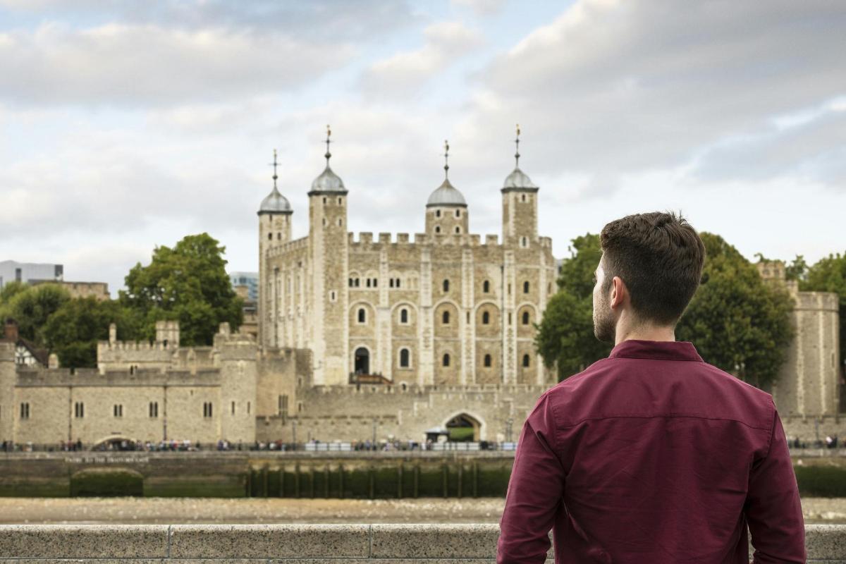 un homme debout devant un château