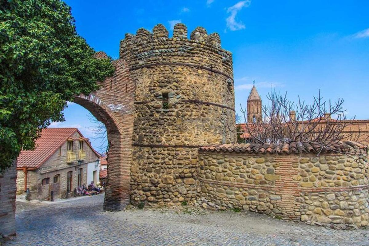 Stará kamenná zeď s obloukem a budovou