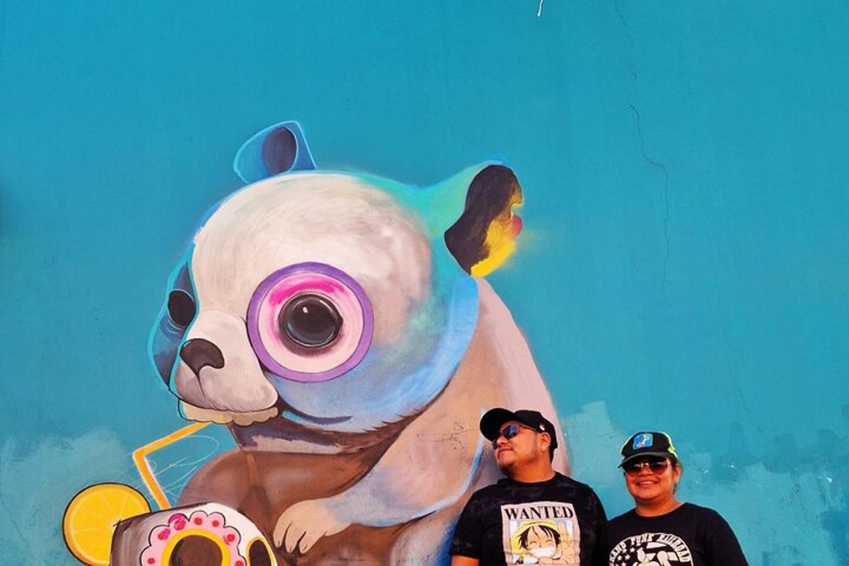 two men standing in front of a painting of a panda bear