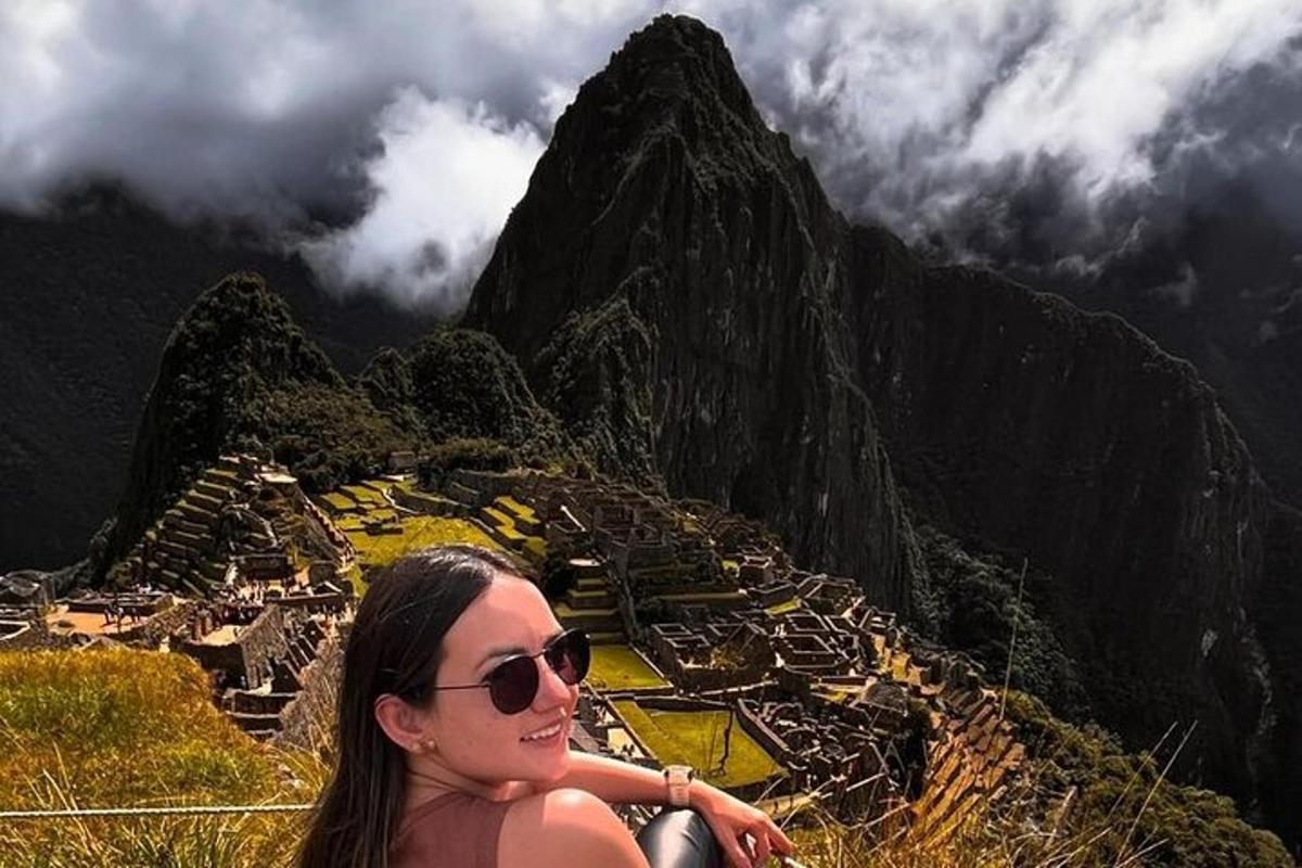 una donna con occhiali da sole seduta in cima a una montagna