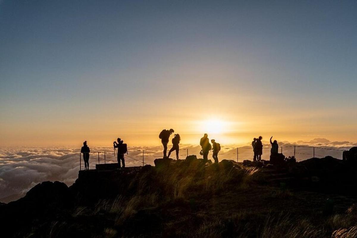 Un grupo de personas de pie en la cima de una montaña al atardecer.