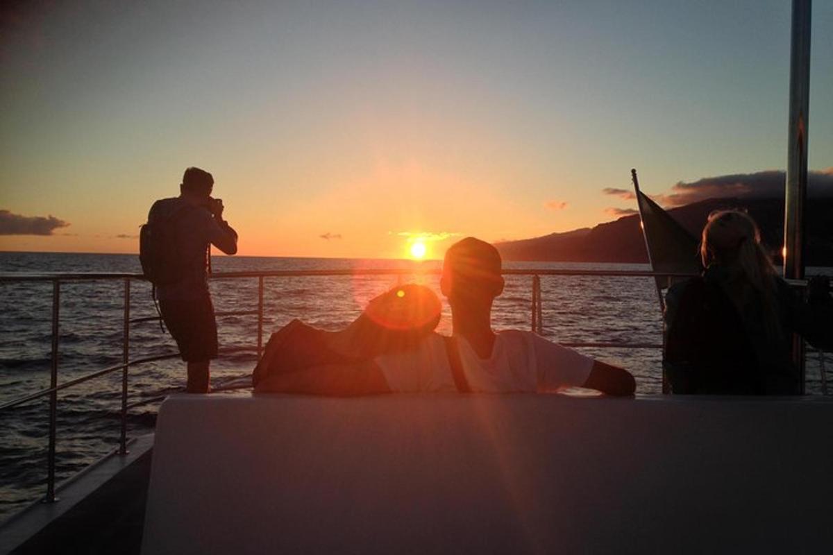 Un hombre tomando una fotografía del atardecer en un barco.