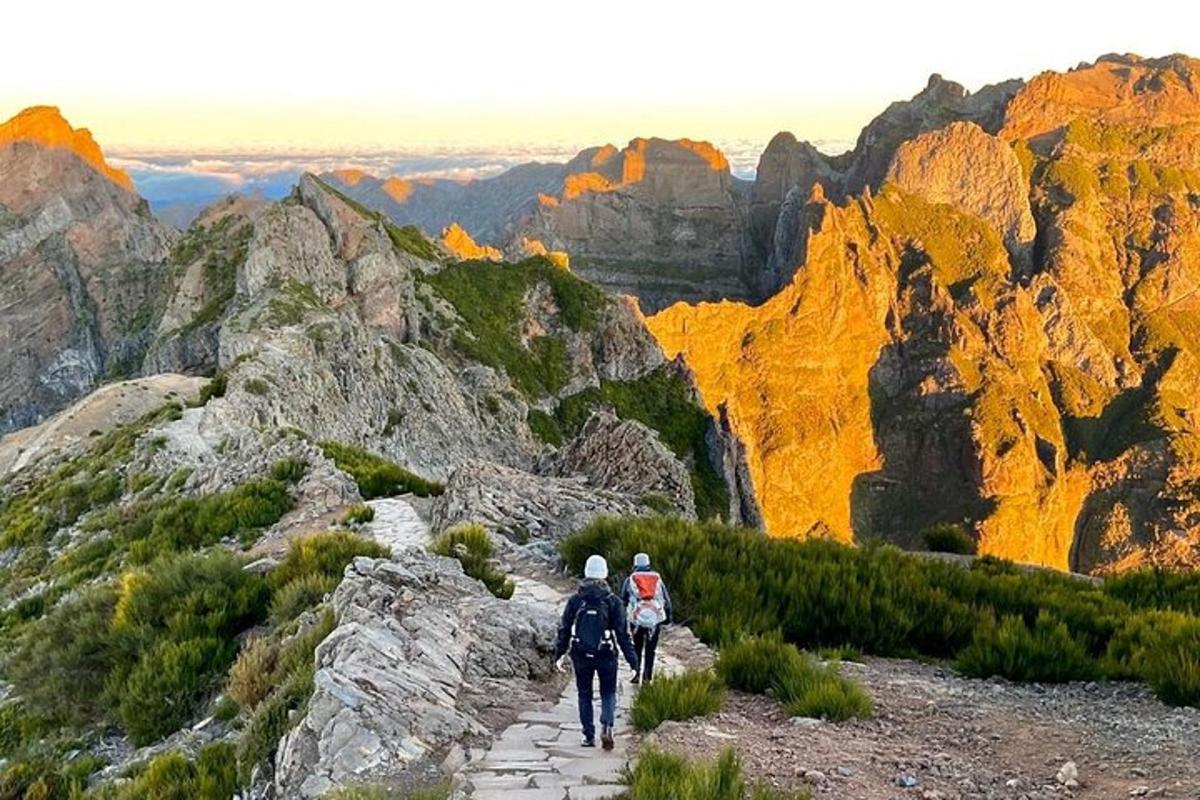 duas pessoas caminhando por uma trilha em uma montanha