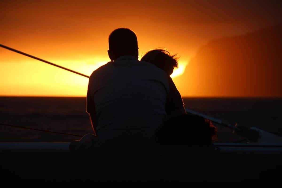 Un hombre y una mujer sentados en un barco mirando la puesta de sol