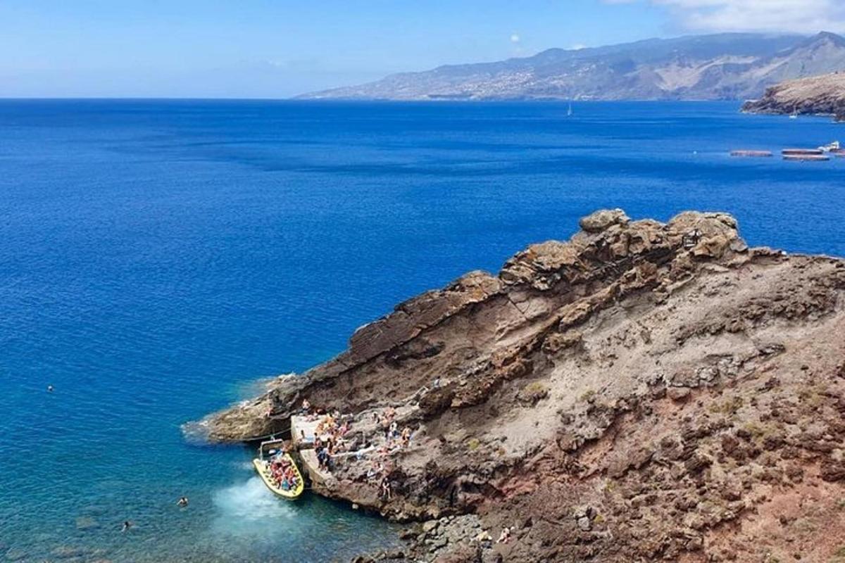 μια βάρκα που κάθεται στο νερό δίπλα σε έναν γκρεμό