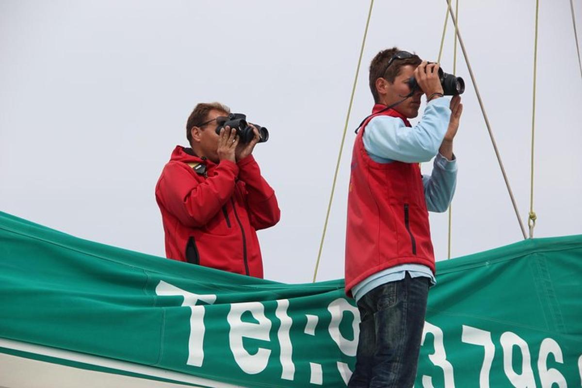 due uomini scattano foto con il binocolo su una barca