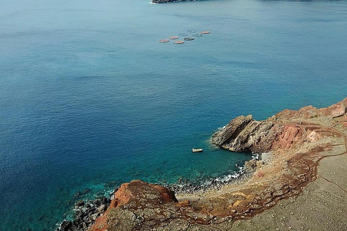 a group of boats in the water near a rocky shore