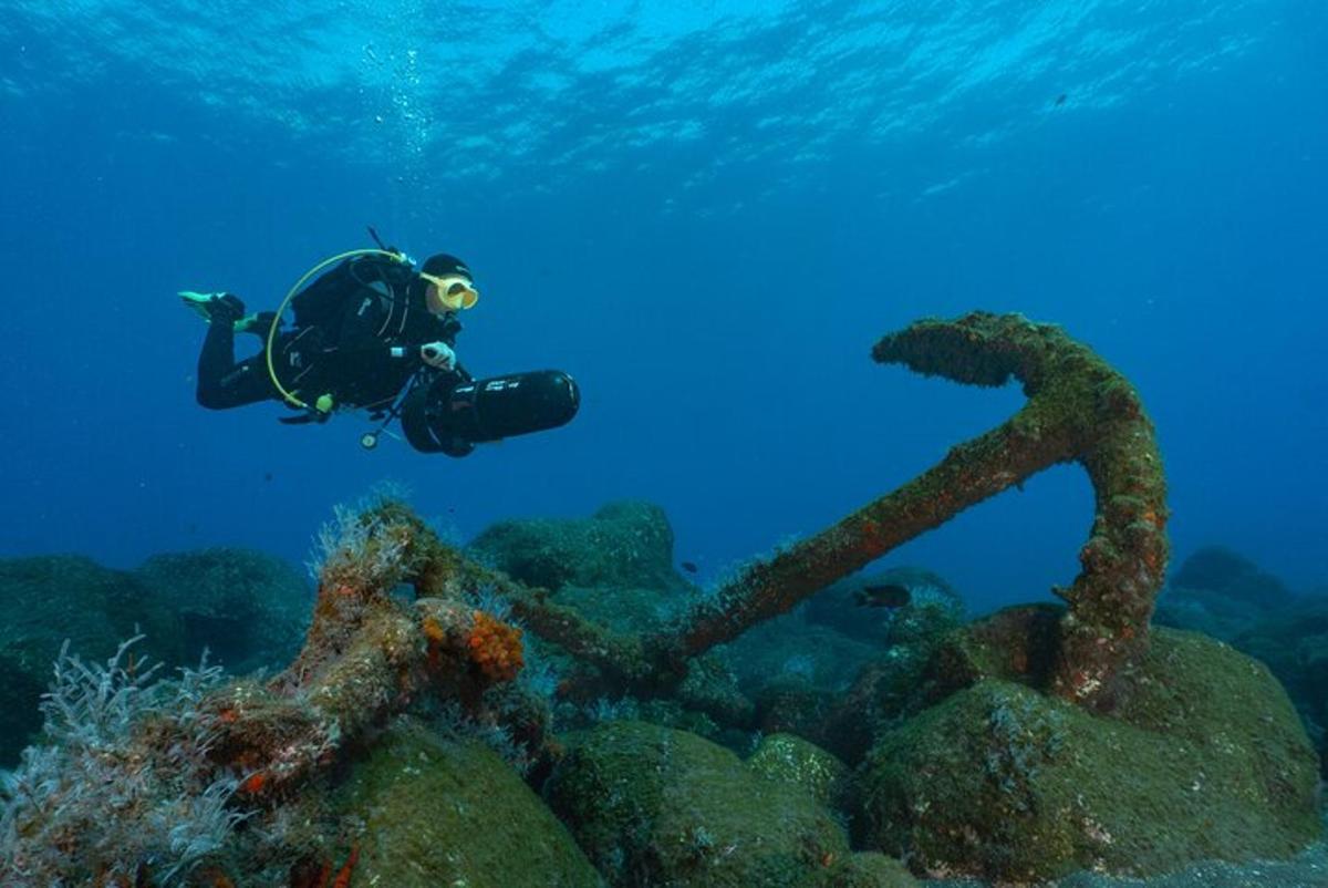 um homem em traje de mergulho nadando sobre um recife de coral