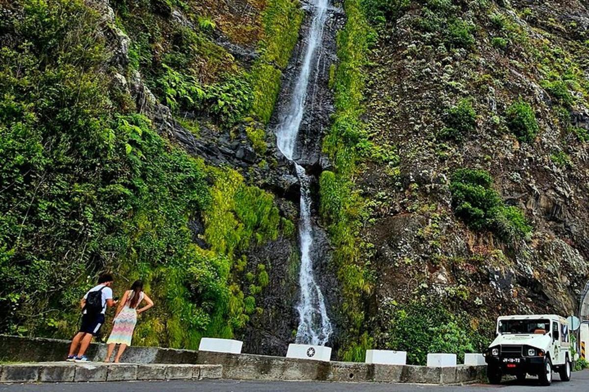 due persone in piedi sul ciglio di una strada vicino a una cascata
