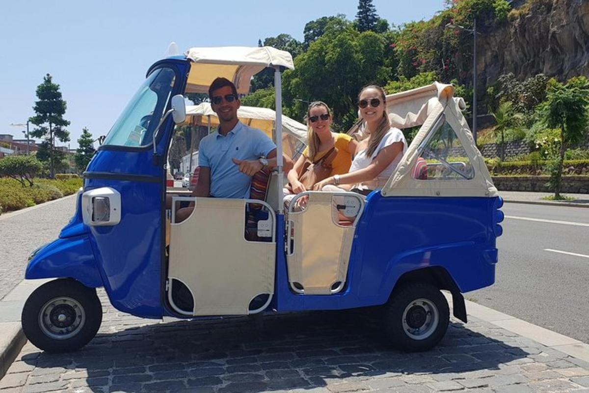 três pessoas andando em um pequeno carrinho de golfe azul e branco