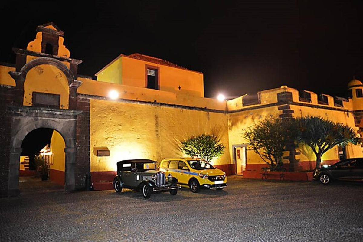 um carro velho estacionado em frente a um prédio à noite
