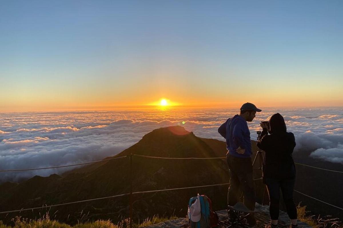 due persone in piedi sulla cima di una montagna al tramonto