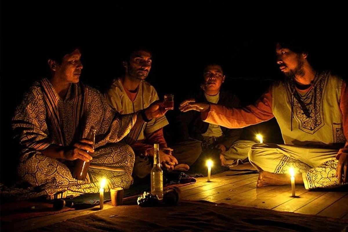 a group of men sitting on the floor with lit candles