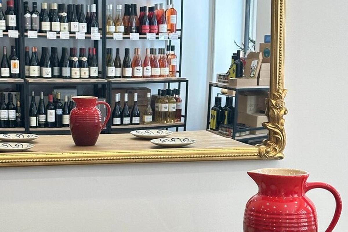 a mirror and two red vases in front of a shelf of wine bottles