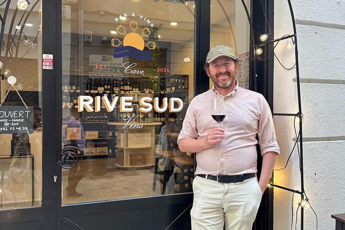 a man holding a glass of wine in front of a shop