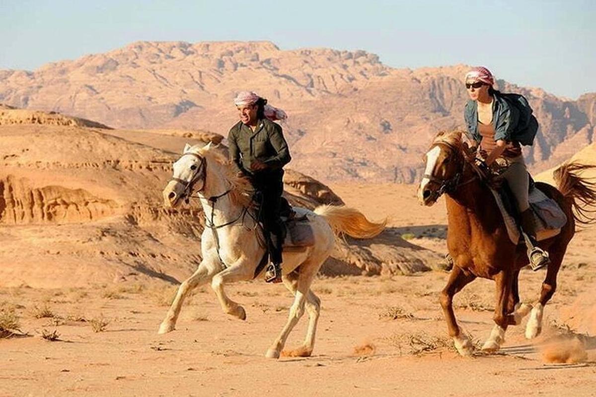 duas pessoas andando a cavalo no deserto