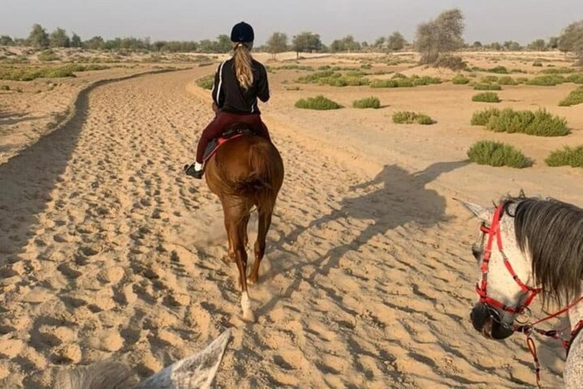 uma mulher cavalgando um cavalo no deserto