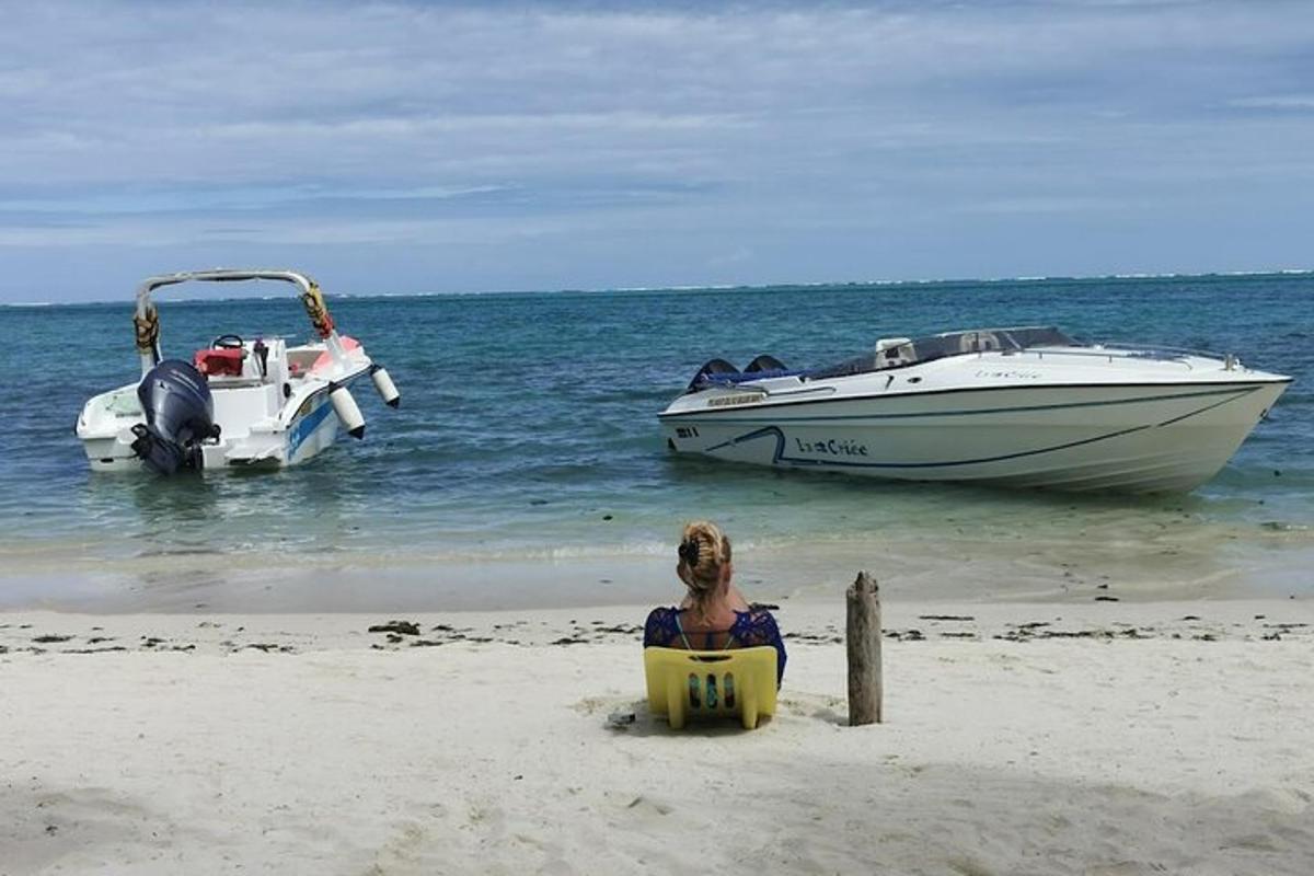 en kvinne som sitter i en stol på en strand med to båter