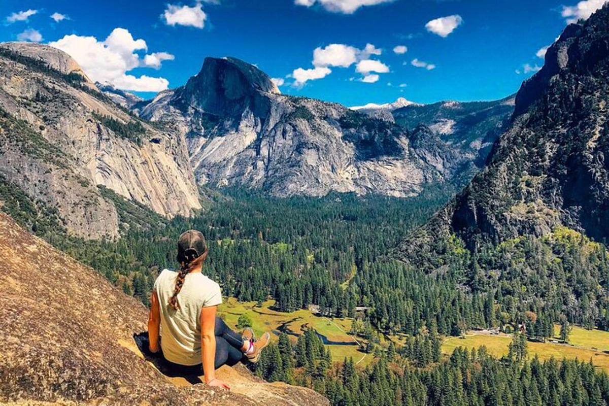 a woman sitting on top of a mountain looking at a valley