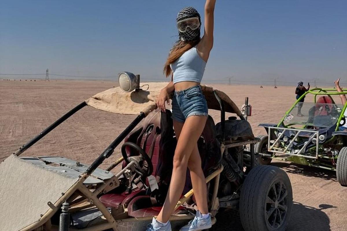 eine Frau, die in der Wüste auf der Motorhaube eines Autos steht
