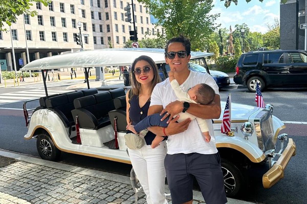 a man and woman holding a baby next to a car