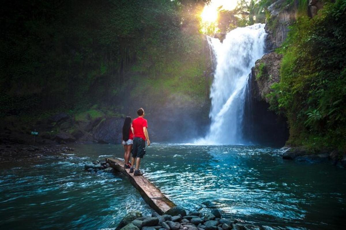 dua orang berdiri di atas jambatan di hadapan air terjun