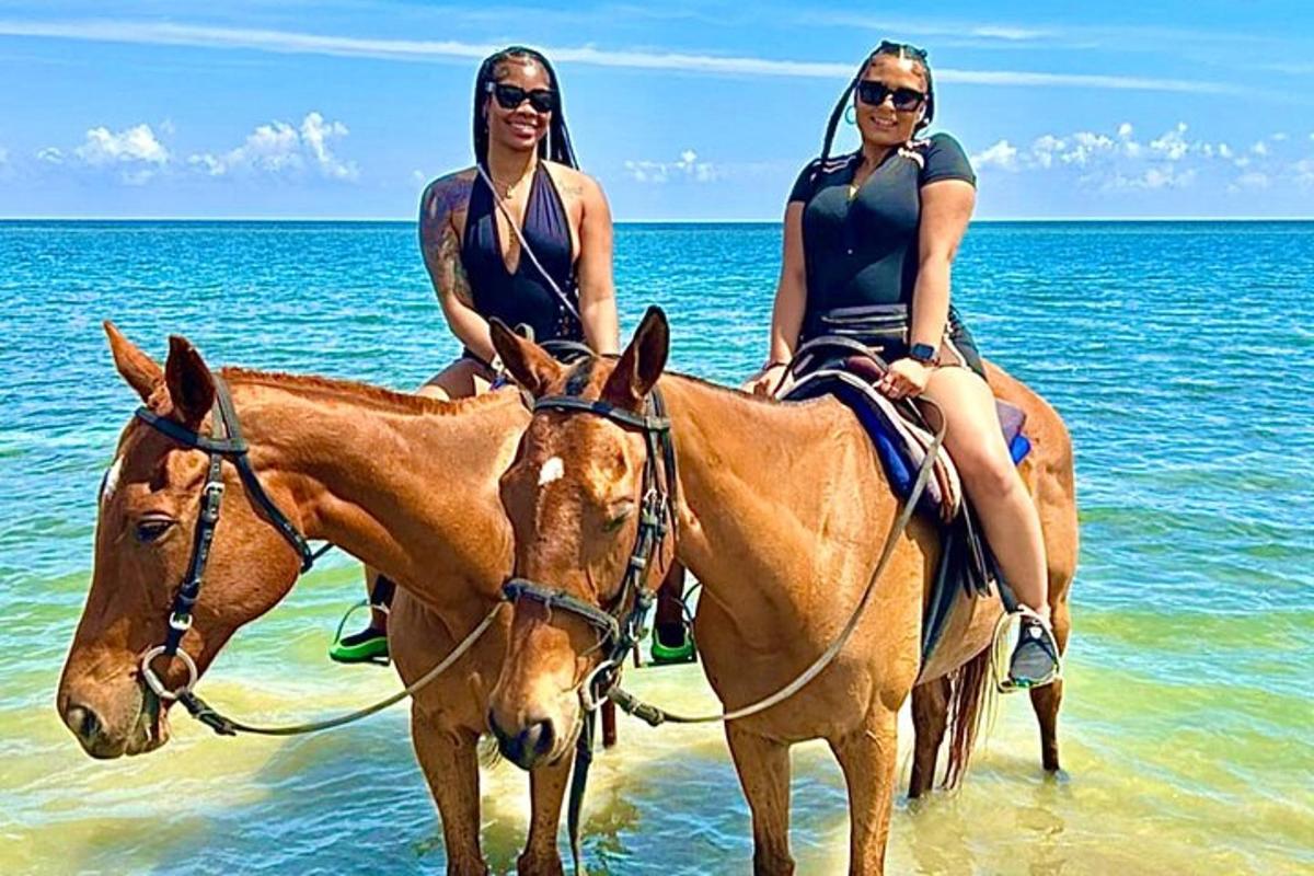 due donne a cavallo nell'acqua sulla spiaggia