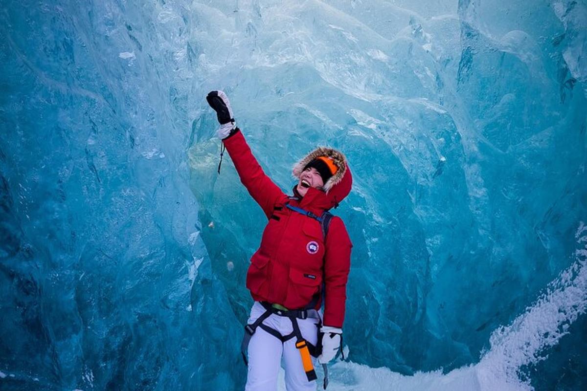 Un hombre está parado frente a una cueva de hielo.