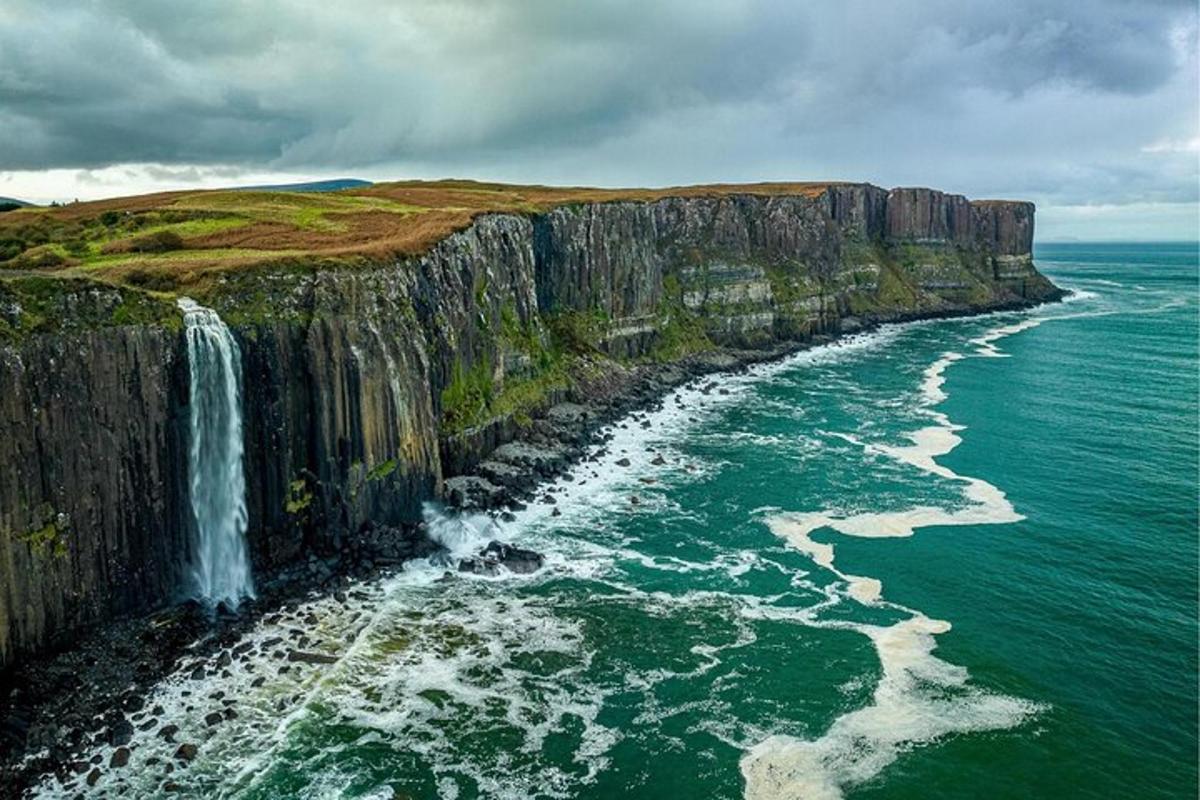 a waterfall on a cliff next to the ocean