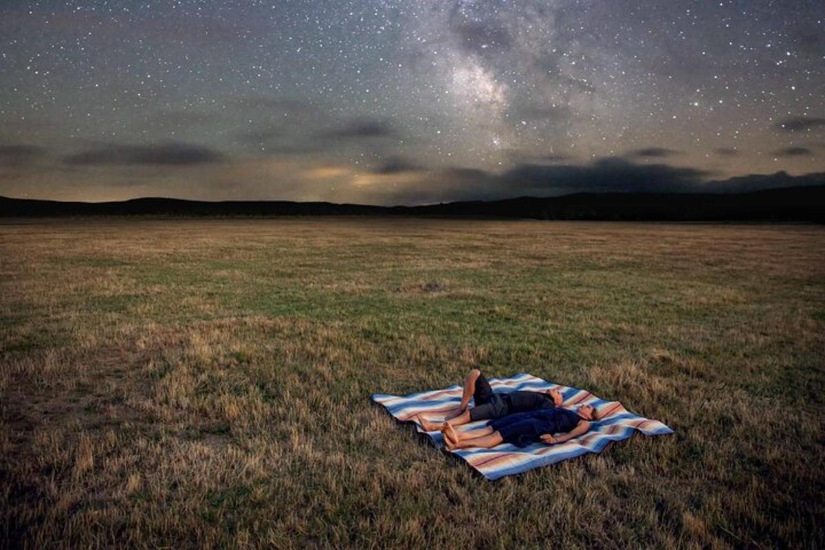a person laying on a blanket in a field under the stars