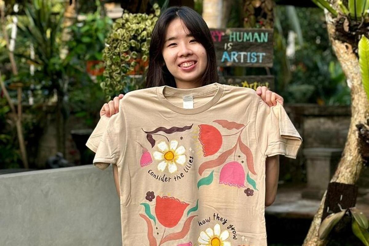 a young girl is holding a t shirt